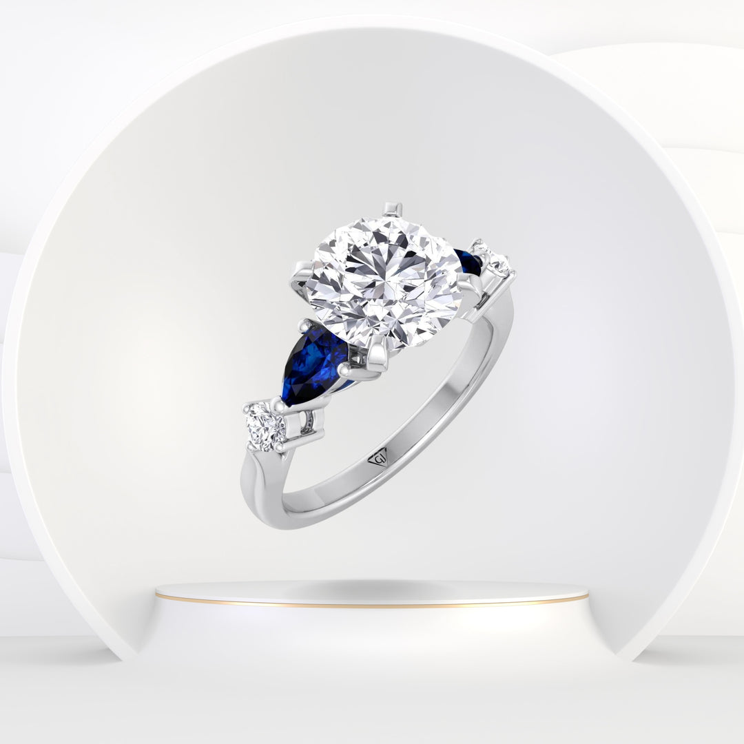 Cherie - (2.57Ct T.W.) Round Cut Diamond Engagement Ring with Blue Sapphire Pear Shape Sidestones - Gem Jewelers Co