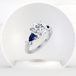 Cherie - (2.57Ct T.W.) Round Cut Diamond Engagement Ring with Blue Sapphire Pear Shape Sidestones - Gem Jewelers Co