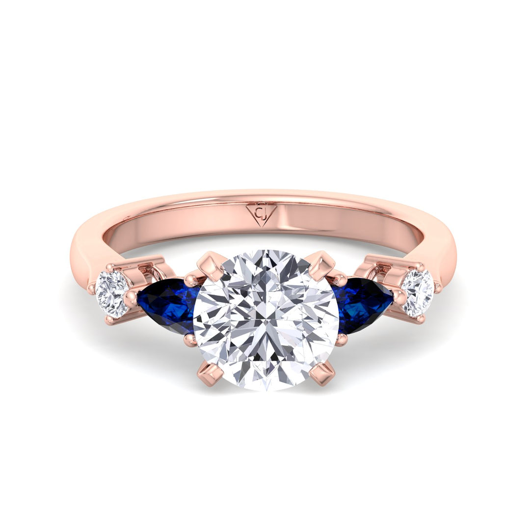 round-cut-diamond-engagement-ring-with-blue-sapphire-pear-shape-sidestones-in-rose-gold